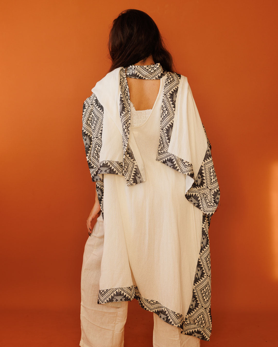 פונצו צעיף לבן, עם עיטור גיאומטרי שחור לבן מנצנץ בשוליים לאישה